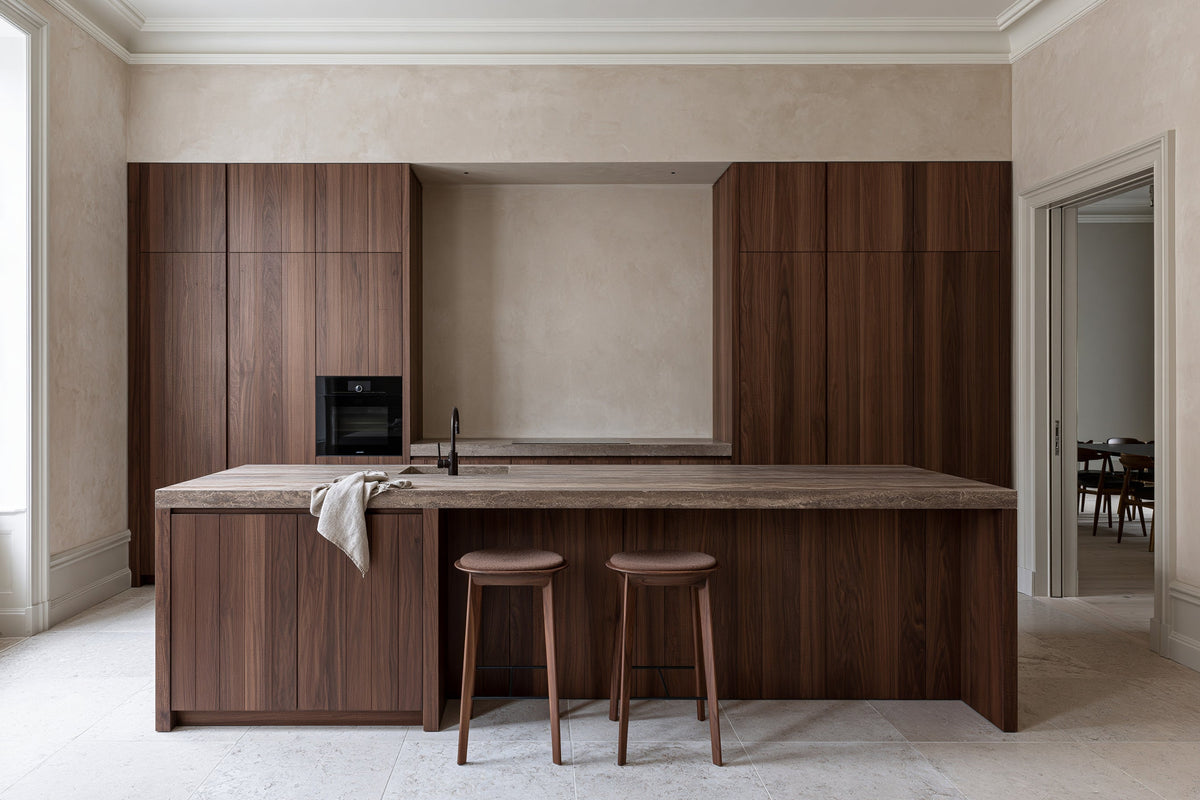 A kitchen with walnut cabinetry, a walnut island with a stone top and two counter stools
