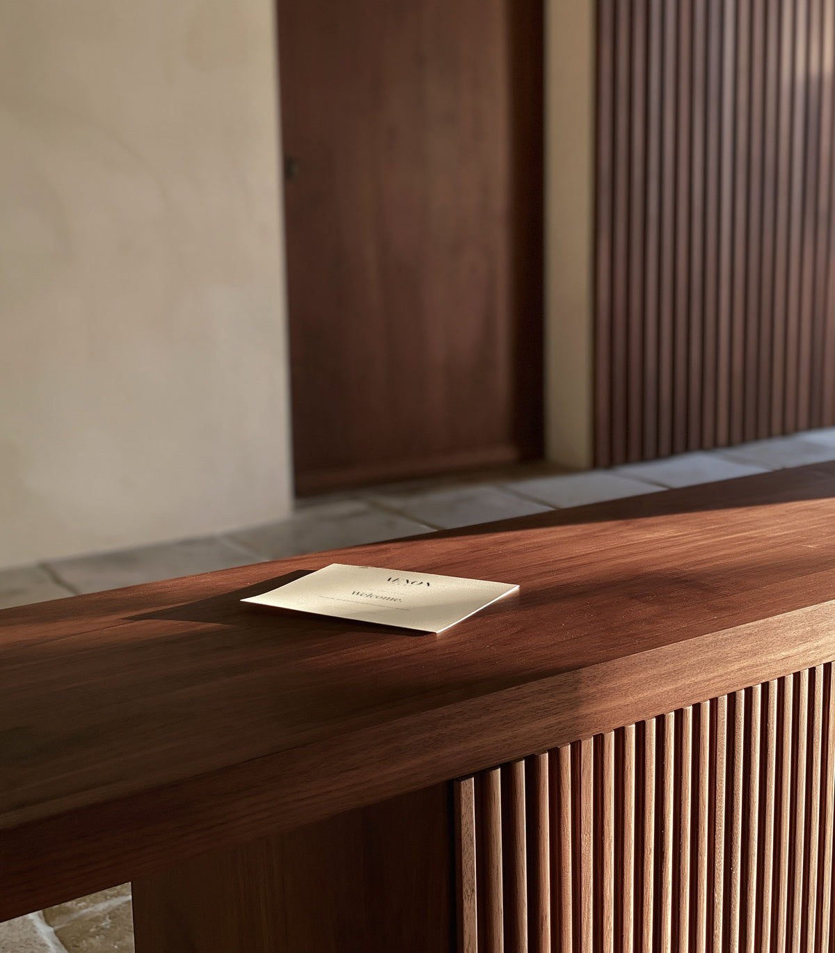 The first AENON letter on a walnut console by the front door